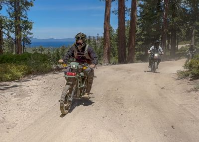 dirt bikers riding on a trail overlooking lake tahoe on a sunny day